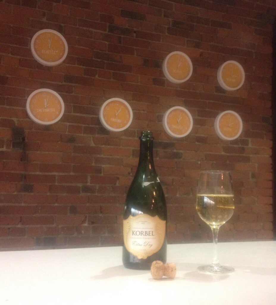 A thumbnail image of a bottle of opened Korbel and a wine glass filled with champagne.  In the background the seven Galvanize clocks.